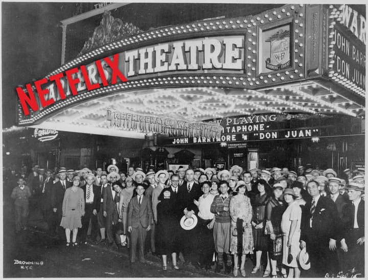 black and white photo from 1926 outside a warners' theatre movie palace with the netflix wordmark over the word warners' on the marquee